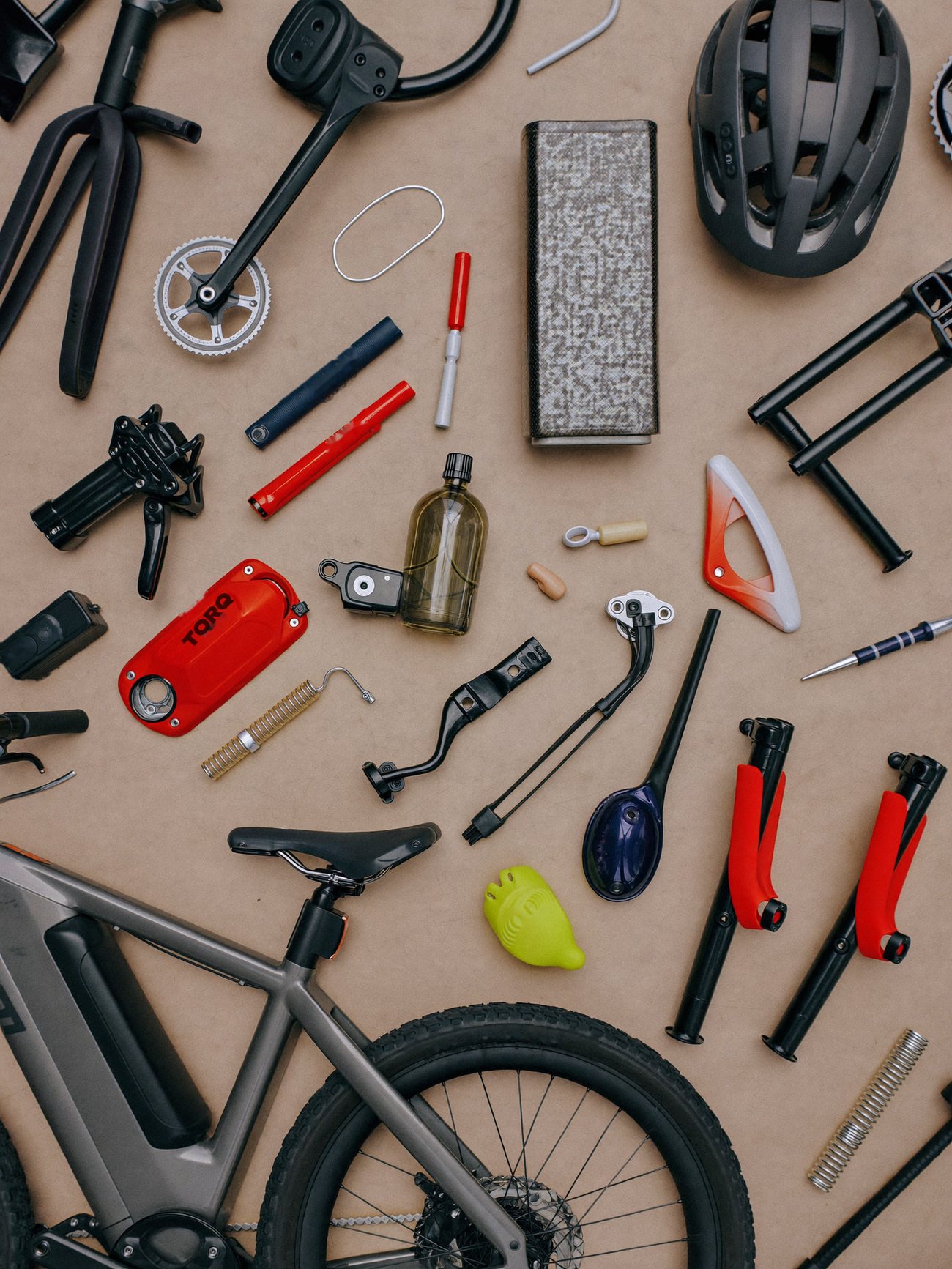 Flat lay of e-bike parts and tools on brown paper, with a red battery lid printed TORQ