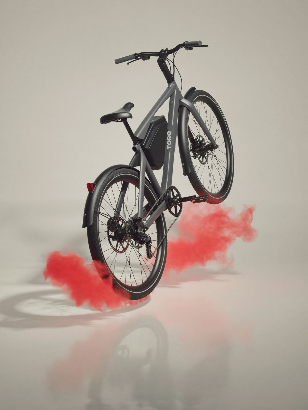 Grey e-bike lifted off the ground in a studio with red smoke at the wheels