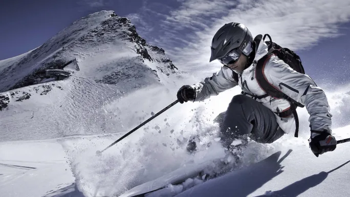 A skier in a helmet carving through powder in black and white