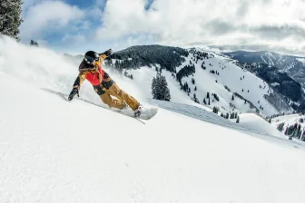 A snowboarder riding a wide open slope