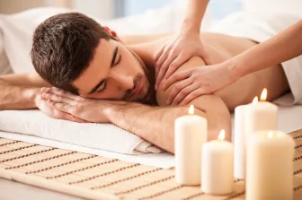 A man relaxing during a massage beside candles
