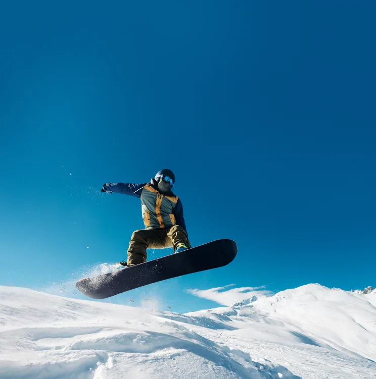 A snowboarder in mid-air against a deep blue sky
