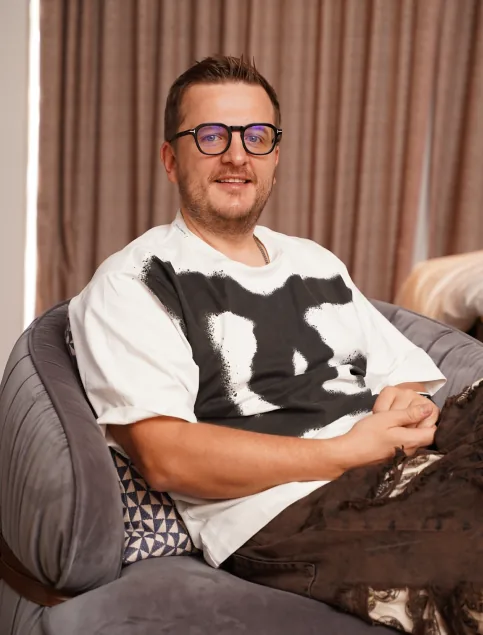 Portrait of Ilya Prusenko in round glasses sitting in an armchair