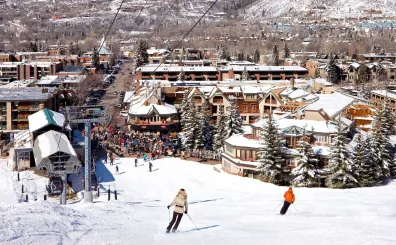 Skiers on a groomed slope above the village of Aspen