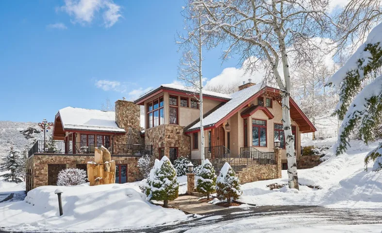 Stone and timber mountain residence surrounded by snowy trees